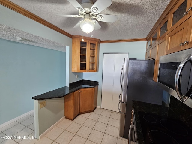 kitchen with a peninsula, brown cabinetry, stainless steel microwave, glass insert cabinets, and crown molding