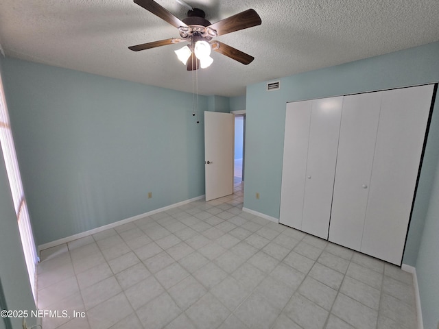 unfurnished bedroom with baseboards, visible vents, ceiling fan, a textured ceiling, and a closet