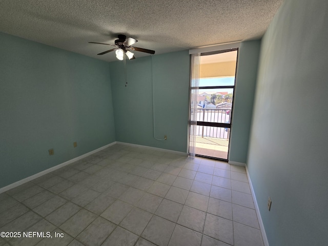 unfurnished room with light tile patterned floors, a ceiling fan, a textured ceiling, a wall of windows, and baseboards