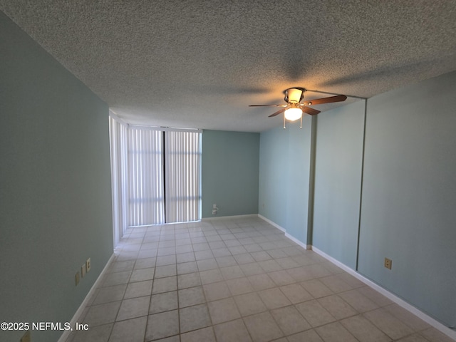 empty room featuring a ceiling fan, a textured ceiling, baseboards, and light tile patterned floors