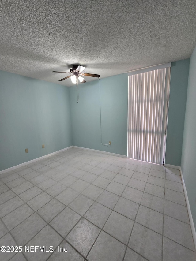 spare room with ceiling fan, a textured ceiling, and baseboards