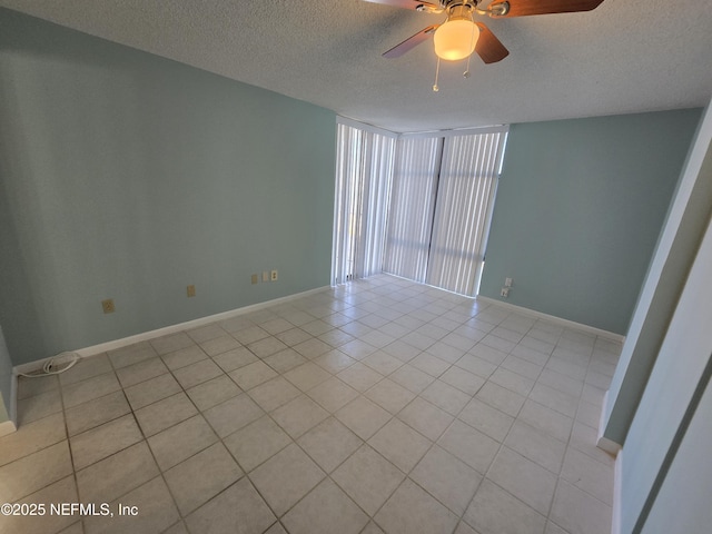 empty room with ceiling fan, a textured ceiling, baseboards, and light tile patterned floors