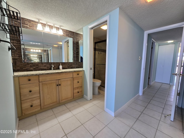 bathroom featuring a textured ceiling, vanity, baseboards, tile patterned floors, and a stall shower