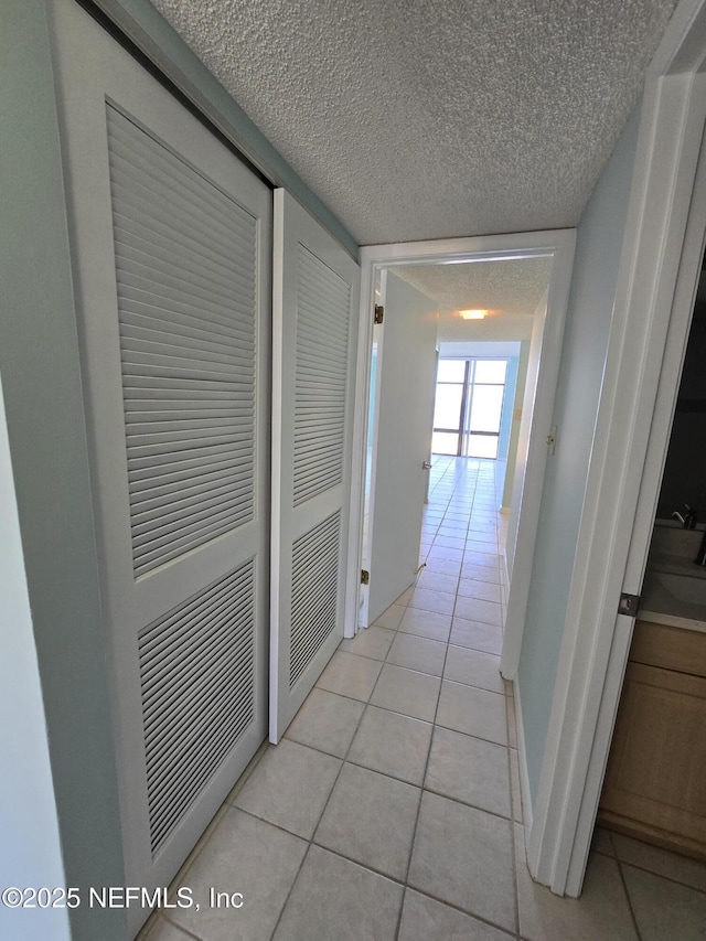 hallway featuring light tile patterned floors and a textured ceiling