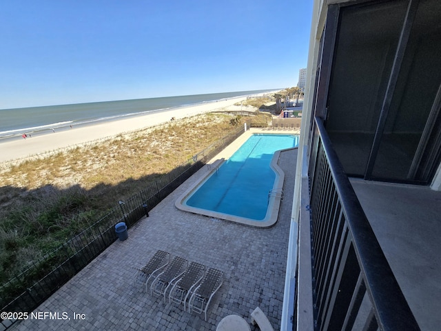 balcony with a water view, a patio area, and a beach view