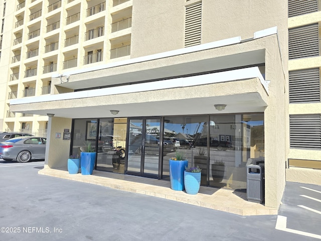 view of exterior entry featuring uncovered parking and stucco siding