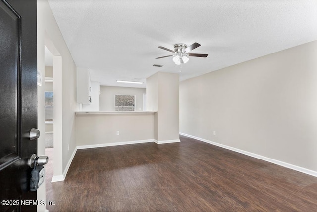 unfurnished living room featuring ceiling fan, dark wood-type flooring, and a textured ceiling