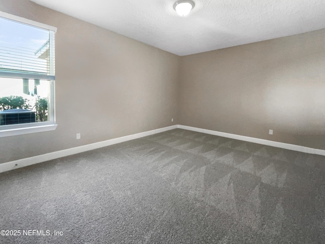 unfurnished room featuring a textured ceiling and dark colored carpet