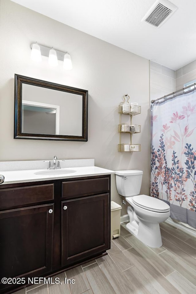 bathroom featuring toilet, vanity, and a shower with curtain