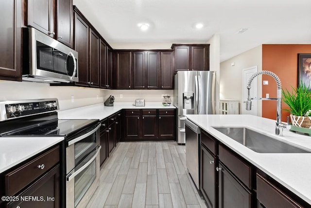 kitchen with sink, dark brown cabinets, light hardwood / wood-style floors, and stainless steel appliances