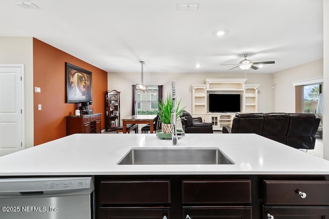 kitchen featuring decorative light fixtures, ceiling fan, stainless steel dishwasher, a center island with sink, and dark brown cabinets