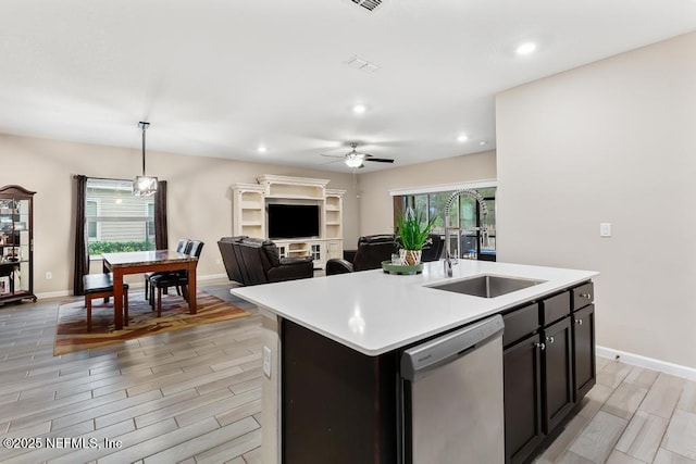 kitchen featuring stainless steel dishwasher, ceiling fan, decorative light fixtures, sink, and an island with sink