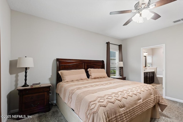 bedroom with dark carpet, ensuite bath, and ceiling fan