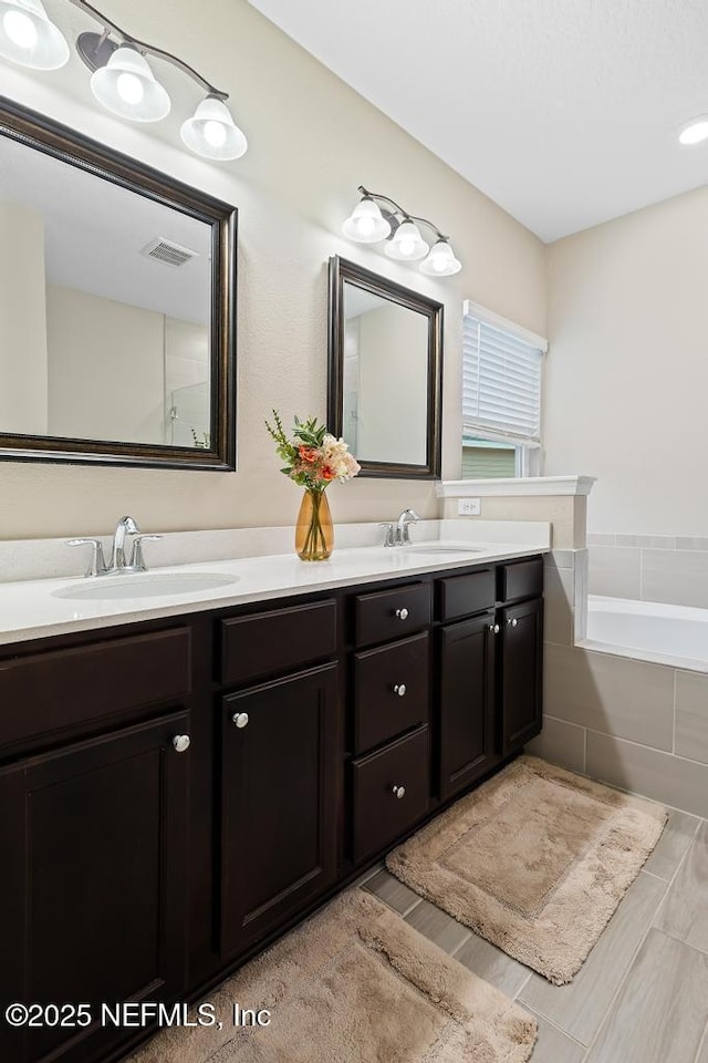 bathroom with vanity and tiled bath