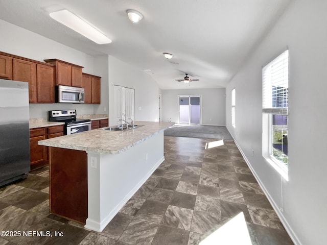 kitchen with sink, a wealth of natural light, stainless steel appliances, and a kitchen island with sink