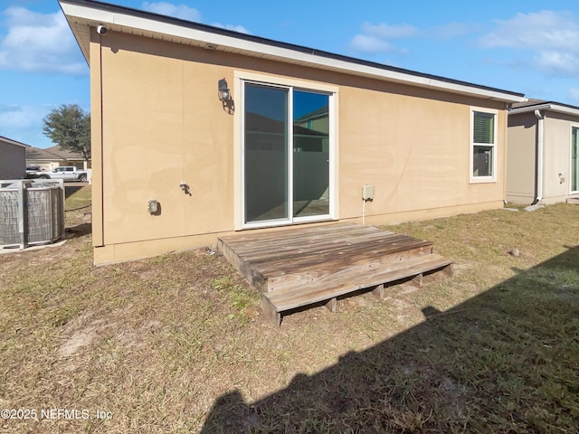 back of house featuring a wooden deck, cooling unit, and a lawn