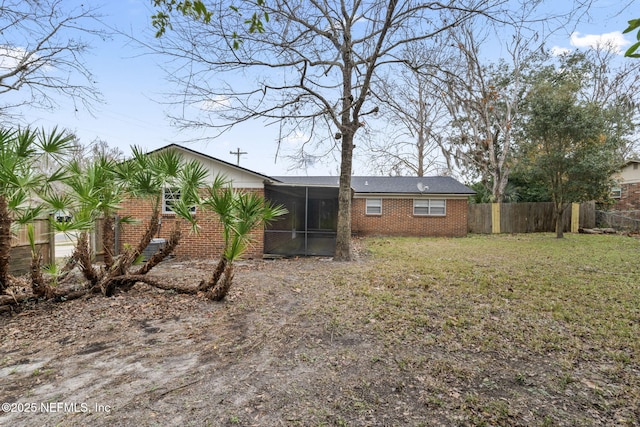 rear view of property featuring a sunroom and a lawn