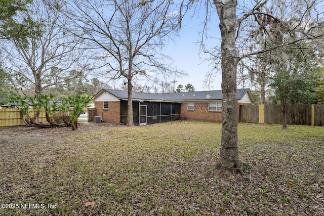 back of house featuring a sunroom, a lawn, and central AC unit