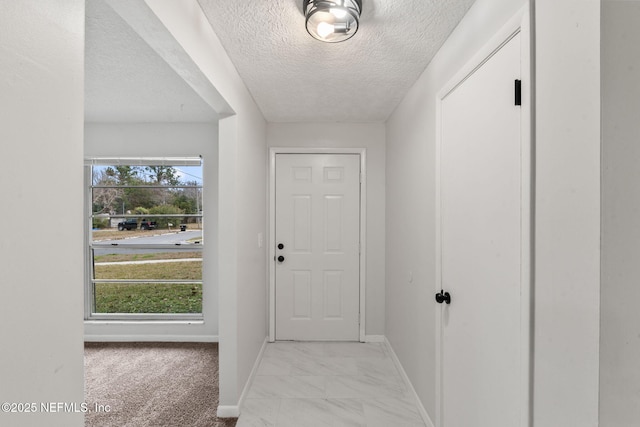 entryway with light colored carpet and a textured ceiling