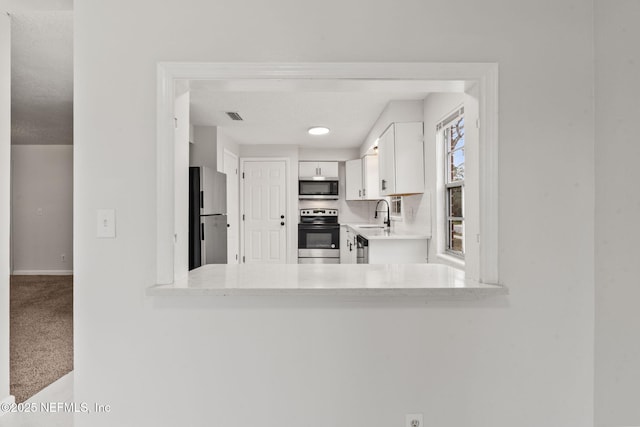 kitchen with carpet, white cabinets, stainless steel appliances, sink, and kitchen peninsula