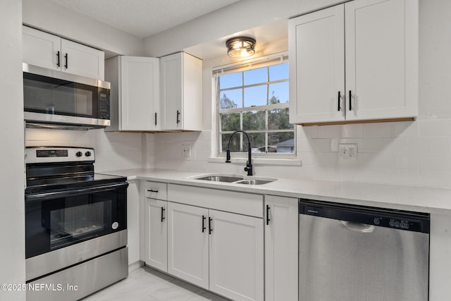 kitchen featuring white cabinets, backsplash, appliances with stainless steel finishes, and sink