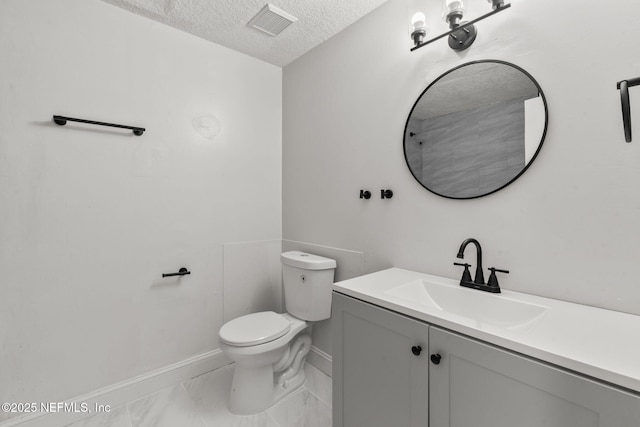 bathroom with vanity, toilet, and a textured ceiling