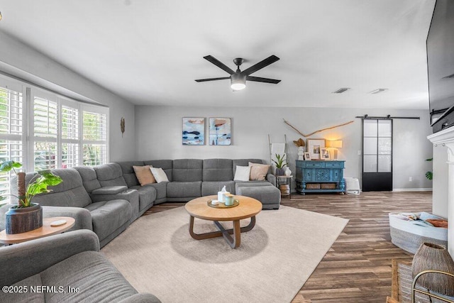 living room featuring hardwood / wood-style flooring, a barn door, and ceiling fan