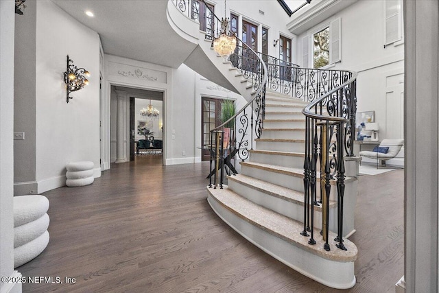 stairway with a chandelier, a towering ceiling, and hardwood / wood-style floors