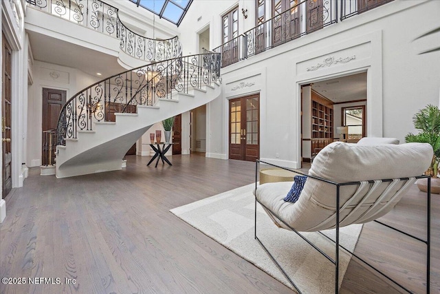 living room featuring french doors, wood-type flooring, and a high ceiling