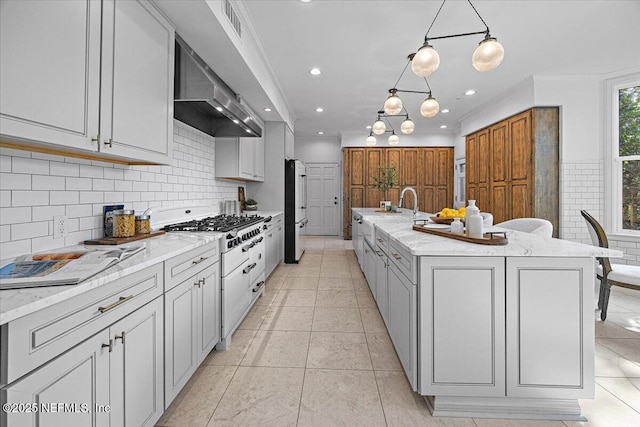 kitchen with a spacious island, pendant lighting, decorative backsplash, fridge, and light stone counters