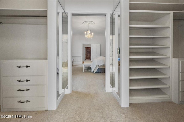 spacious closet with light carpet and an inviting chandelier