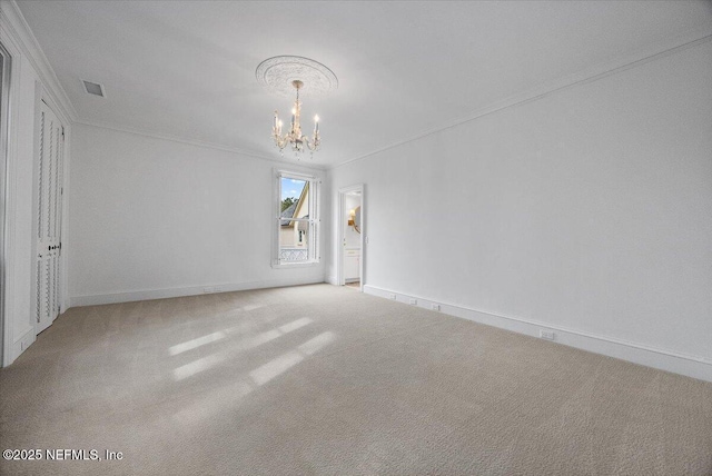 carpeted empty room featuring a chandelier and ornamental molding