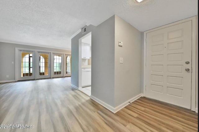 foyer entrance with light hardwood / wood-style floors and a textured ceiling