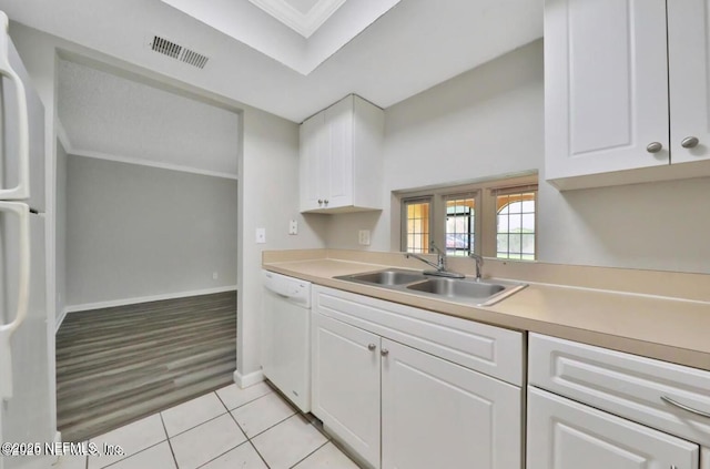 kitchen with light tile patterned floors, white appliances, crown molding, white cabinets, and sink