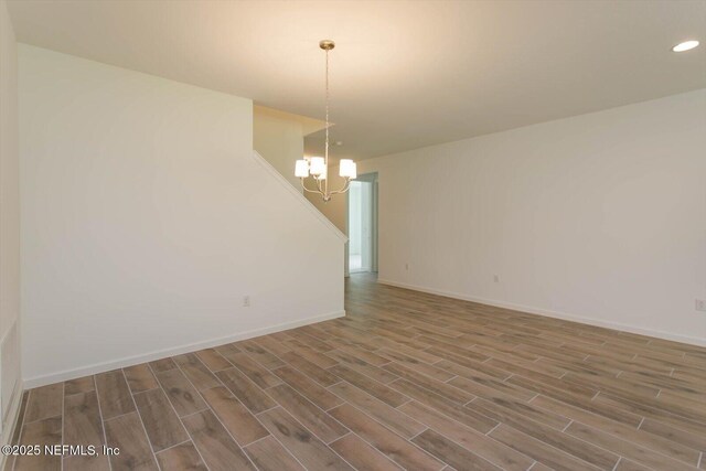 spare room with a chandelier, wood finished floors, baseboards, and recessed lighting