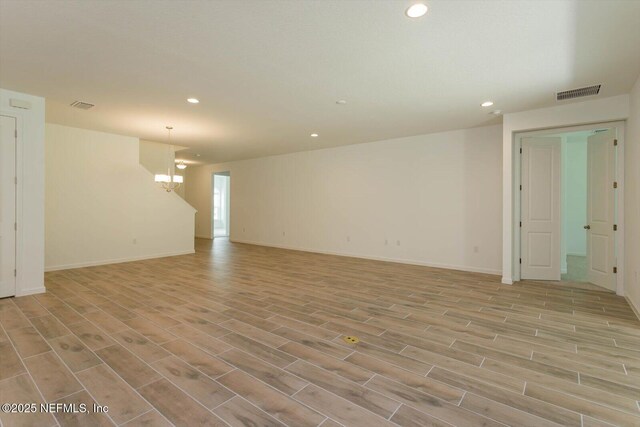empty room with recessed lighting, light wood-style flooring, a chandelier, and baseboards