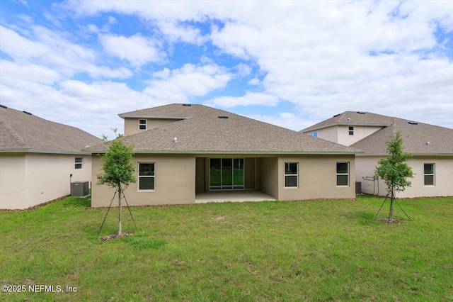 back of house with cooling unit, a patio area, stucco siding, roof with shingles, and a lawn