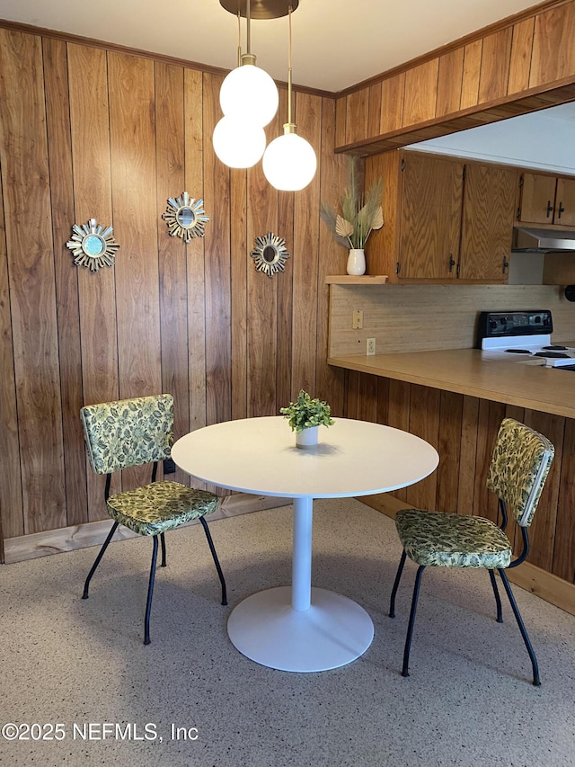 dining area with breakfast area, light speckled floor, and wood walls