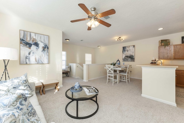 living room featuring sink, light colored carpet, and a textured ceiling