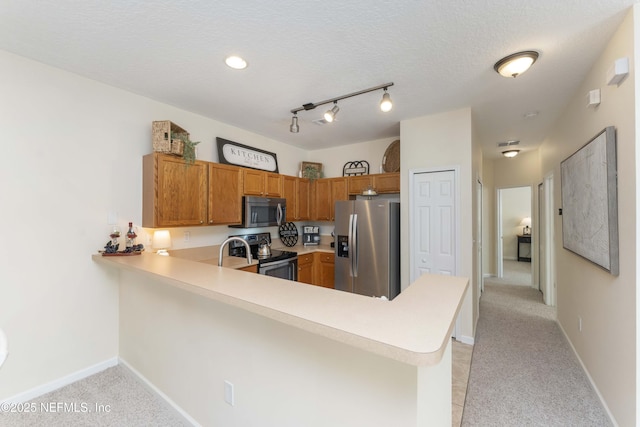 kitchen with appliances with stainless steel finishes, light carpet, a textured ceiling, and kitchen peninsula