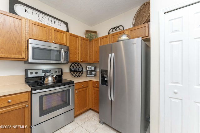 kitchen with light tile patterned flooring, appliances with stainless steel finishes, and a textured ceiling