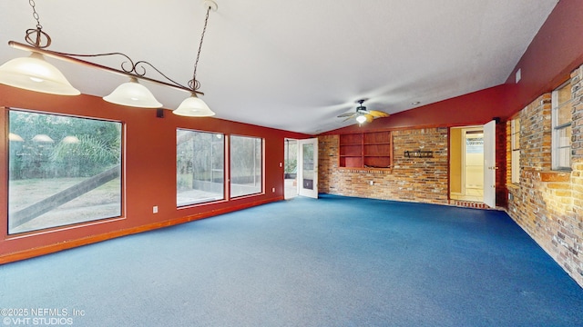 unfurnished living room featuring brick wall, carpet, lofted ceiling, built in features, and ceiling fan