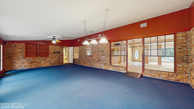 unfurnished living room with built in shelves, carpet flooring, brick wall, and ceiling fan