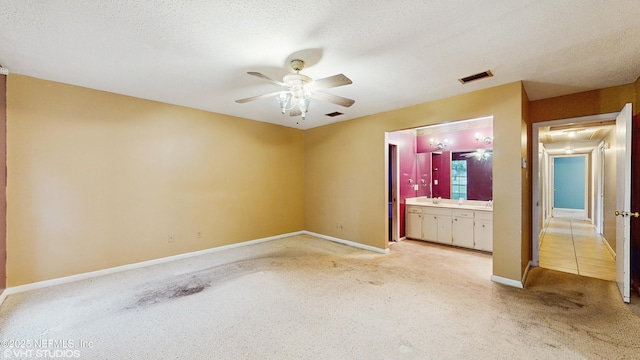 unfurnished bedroom featuring ceiling fan, a textured ceiling, and ensuite bathroom