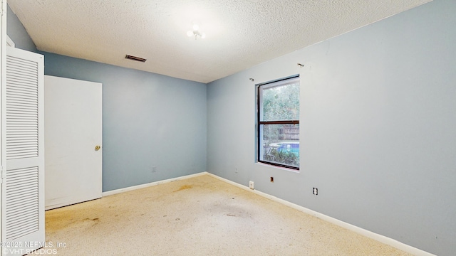 empty room featuring light colored carpet and a textured ceiling