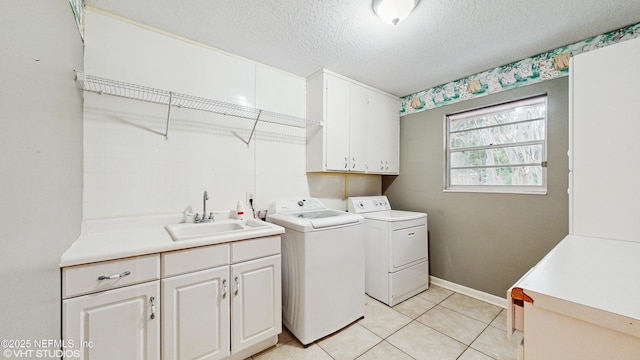 clothes washing area featuring sink, light tile patterned flooring, separate washer and dryer, cabinets, and a textured ceiling