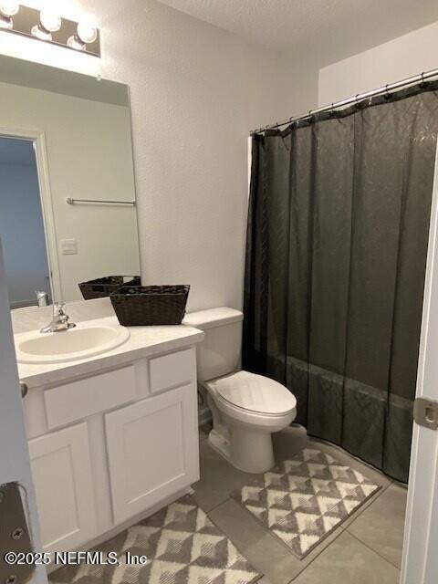 bathroom with curtained shower, vanity, toilet, tile patterned floors, and a textured ceiling