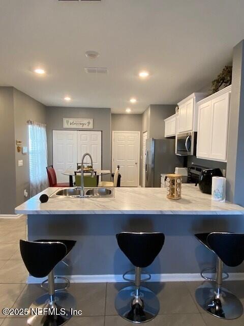 kitchen featuring stainless steel appliances, white cabinetry, sink, and light tile patterned floors