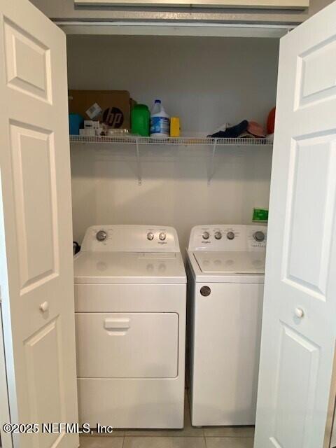 laundry area featuring light tile patterned floors and washing machine and dryer