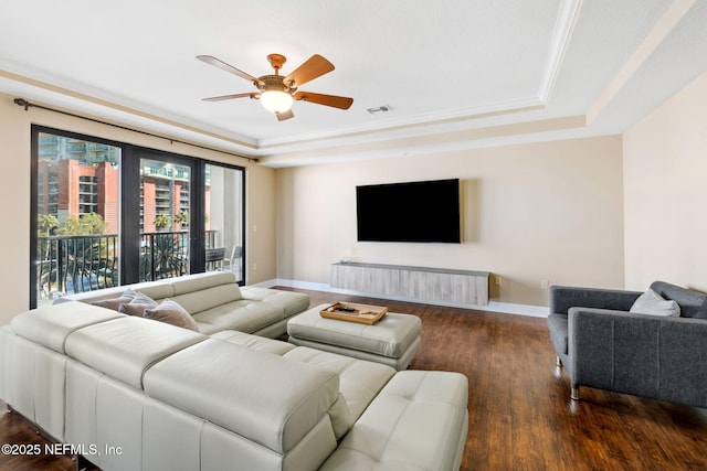 living room with dark wood-type flooring, ornamental molding, a raised ceiling, and ceiling fan